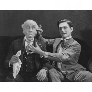 A black and white picture of a magician making an egg appear from a gentleman's mouth.