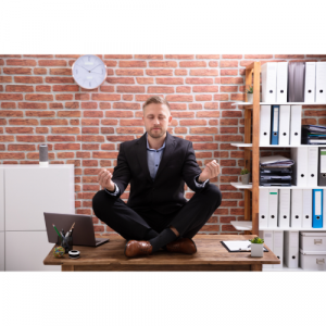 A picture of a man sat on a desk meditating