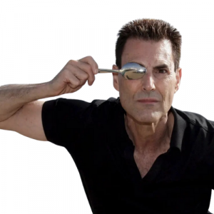 A picture of Uri Geller holding a spoon over his right eye
