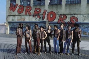 A picture from the film warriors. It shows the gang with graffiti behind them which reads Warriors