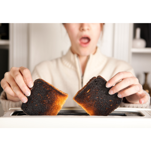 A picture of a woman taking burnt toast out of a toaster.
