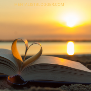 A picture of a book with pages curled into a love heart and there's a sunset in the background.